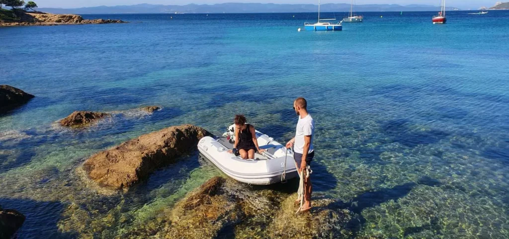 People using inflatable dinghy near rocky shoreline