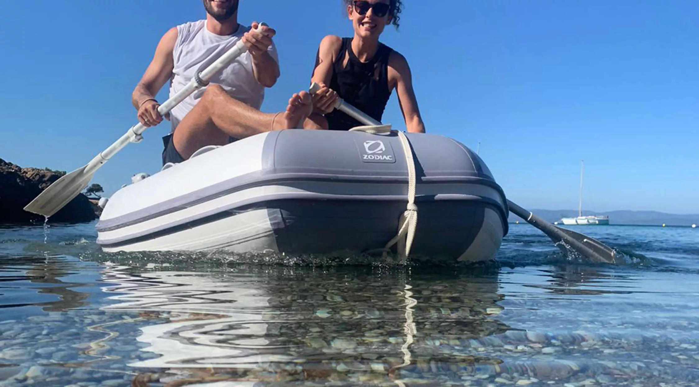 Couple rowing inflatable boat on clear ocean water